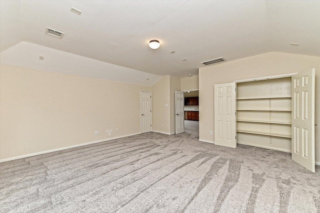 unfurnished bedroom featuring lofted ceiling, carpet, visible vents, and baseboards