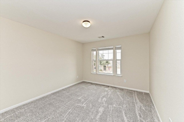 carpeted spare room featuring baseboards and visible vents