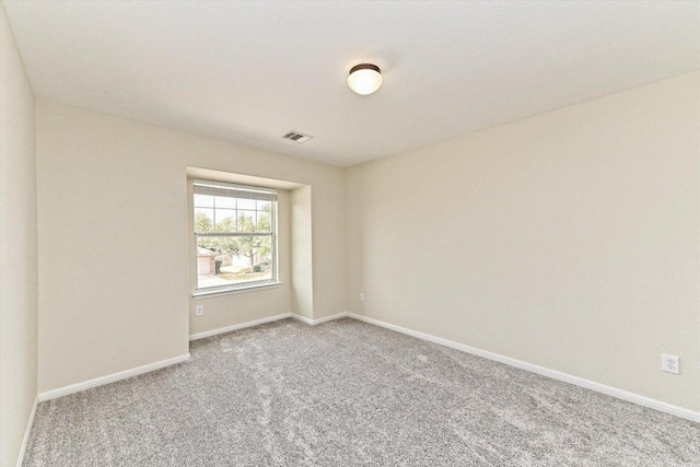 empty room featuring carpet, visible vents, and baseboards