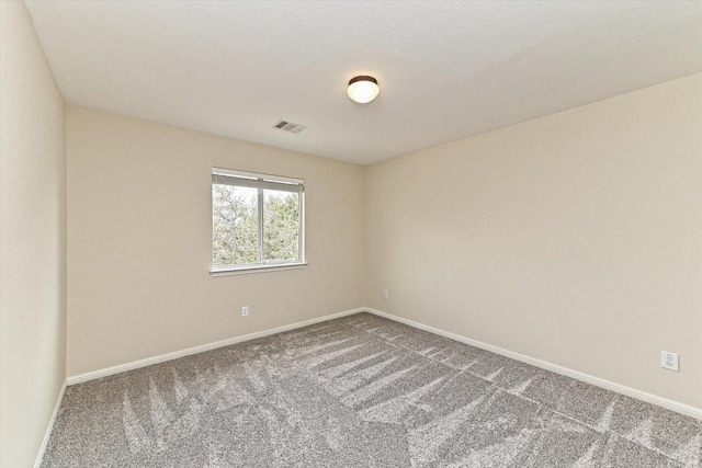 carpeted spare room with visible vents and baseboards