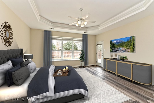 bedroom with visible vents, ornamental molding, wood finished floors, access to exterior, and a tray ceiling