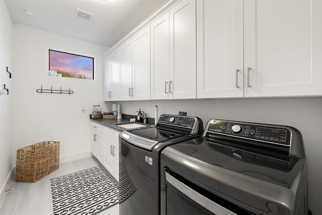 laundry room featuring cabinet space, baseboards, visible vents, separate washer and dryer, and a sink