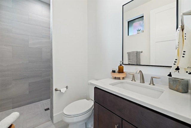 full bathroom featuring toilet, baseboards, tiled shower, and vanity