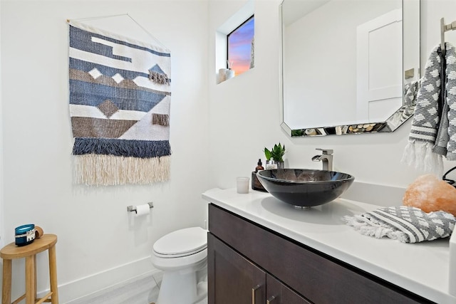 bathroom featuring toilet, baseboards, and vanity