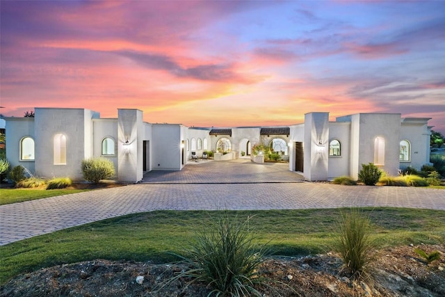 view of front of home featuring a front lawn, decorative driveway, and stucco siding