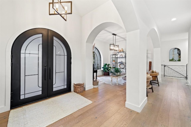 entrance foyer featuring arched walkways, light wood finished floors, and an inviting chandelier