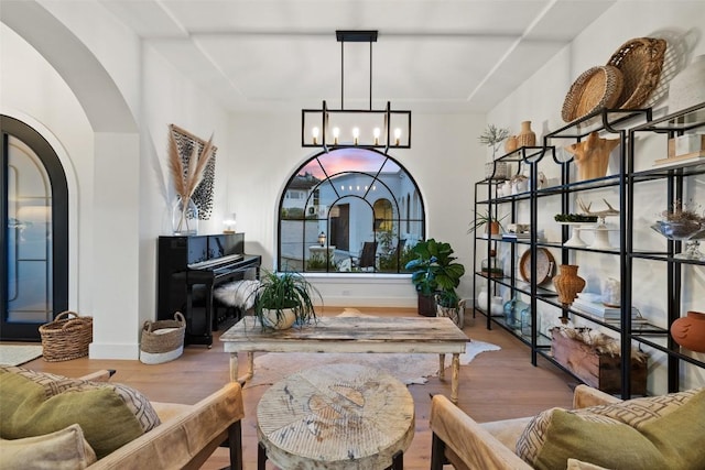 interior space featuring an inviting chandelier, baseboards, arched walkways, and wood finished floors