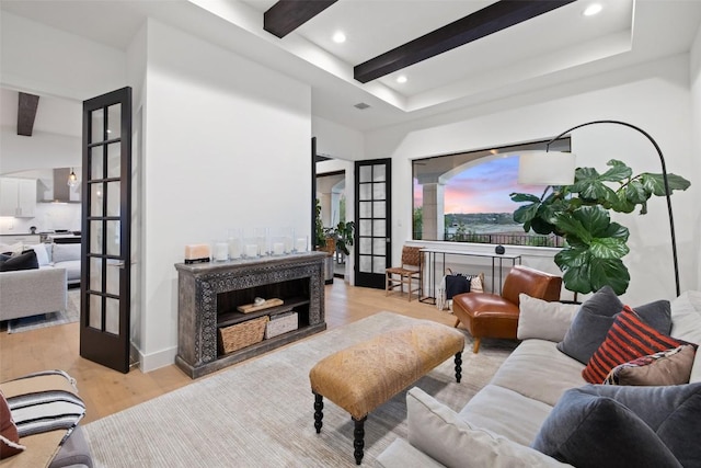 living room with light wood finished floors, recessed lighting, beamed ceiling, and french doors