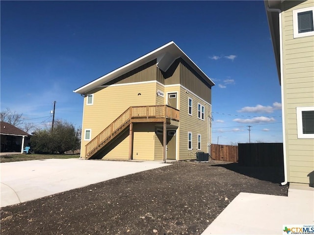 exterior space featuring central AC, fence, a wooden deck, and stairs