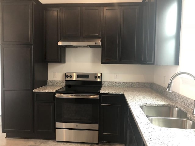 kitchen with dark brown cabinetry, under cabinet range hood, a sink, stainless steel range with electric cooktop, and light stone countertops