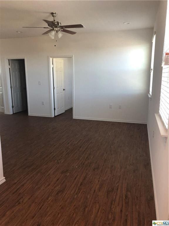 unfurnished room with a ceiling fan, dark wood-style flooring, and baseboards