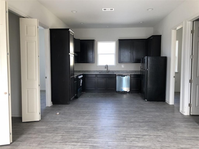 kitchen featuring visible vents, light wood-style flooring, stainless steel dishwasher, freestanding refrigerator, and a sink