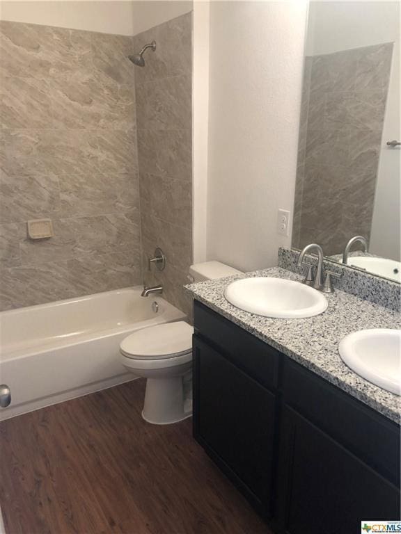 bathroom with toilet, shower / tub combination, a sink, and wood finished floors
