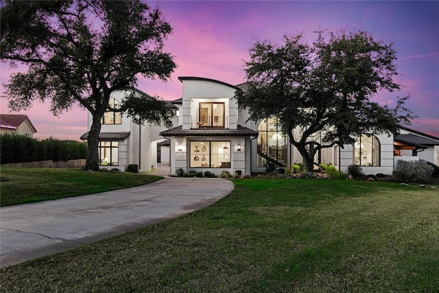 view of front of property with stucco siding, stairway, and a yard