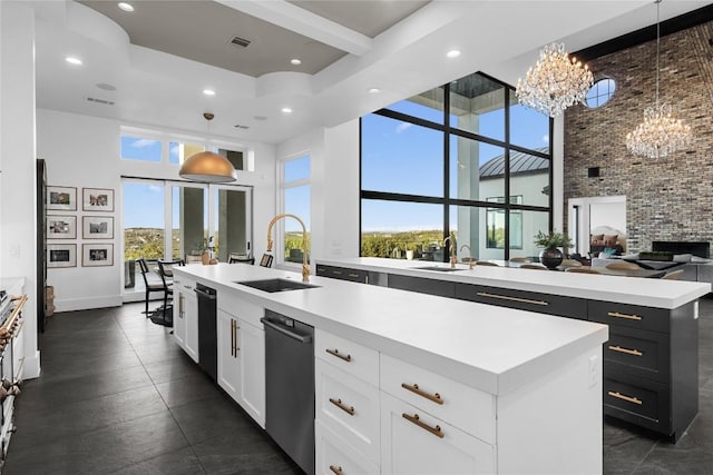 kitchen featuring visible vents, an island with sink, a high ceiling, white cabinetry, and a sink