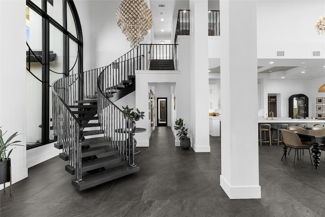 stairs featuring recessed lighting, visible vents, a high ceiling, and baseboards