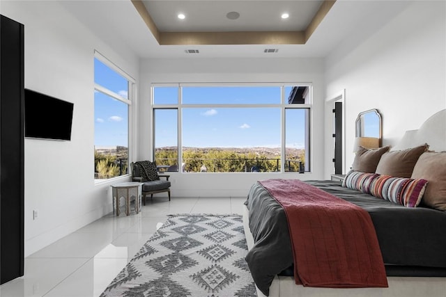 bedroom featuring light tile patterned floors, a tray ceiling, visible vents, and baseboards