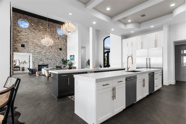 kitchen featuring a fireplace, light countertops, a high ceiling, a kitchen island with sink, and a sink