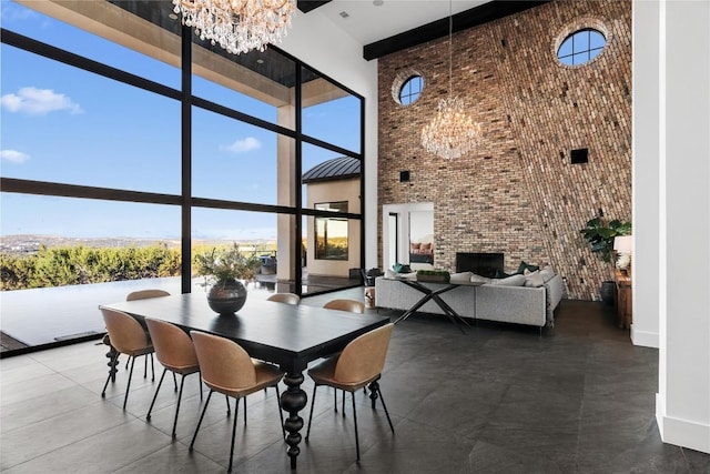 dining room featuring a wall of windows, a high ceiling, brick wall, and an inviting chandelier