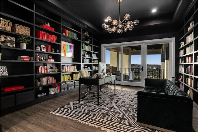 office featuring bookshelves, an inviting chandelier, built in features, and wood finished floors