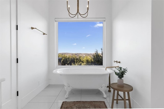 full bath featuring a chandelier, tile patterned flooring, a soaking tub, and baseboards