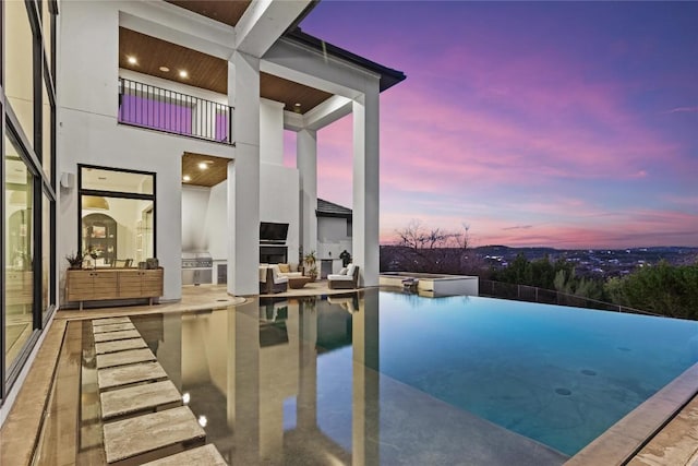 view of pool featuring an infinity pool, a patio area, and an outdoor kitchen