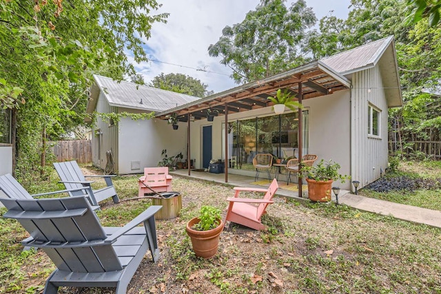 rear view of property featuring metal roof, a patio, and fence