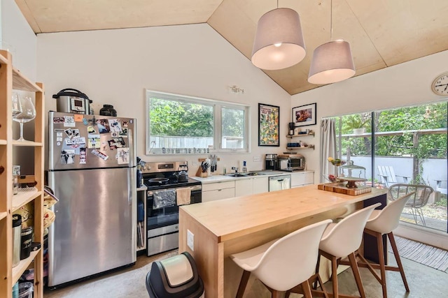 kitchen with a breakfast bar area, lofted ceiling, stainless steel appliances, white cabinets, and wood counters