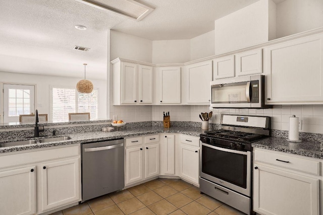 kitchen with visible vents, decorative backsplash, appliances with stainless steel finishes, white cabinetry, and a sink