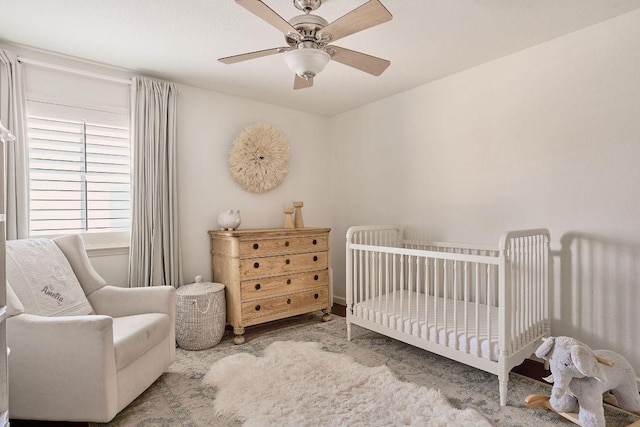 bedroom featuring a nursery area and ceiling fan