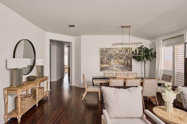 dining area featuring a textured ceiling, visible vents, vaulted ceiling, and wood finished floors