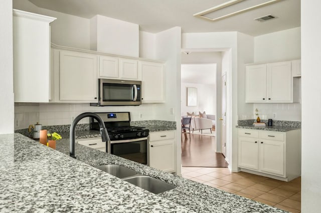 kitchen featuring light tile patterned floors, decorative backsplash, visible vents, stainless steel appliances, and stone counters
