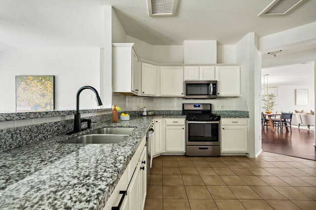 kitchen with a sink, backsplash, white cabinetry, tile patterned flooring, and appliances with stainless steel finishes