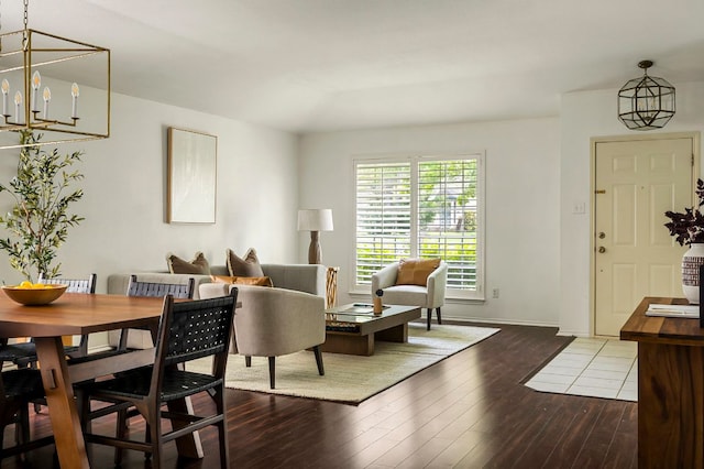 living room with baseboards, an inviting chandelier, and wood-type flooring