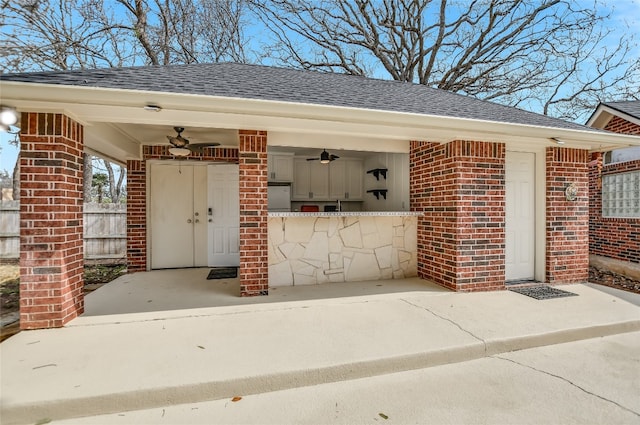 exterior space with concrete driveway, brick siding, a shingled roof, and a ceiling fan