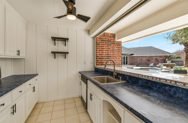 kitchen featuring light tile patterned floors, dark countertops, a sink, and white cabinets