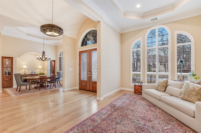 entrance foyer featuring light wood-style flooring, visible vents, a tray ceiling, and crown molding