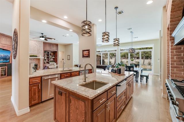 kitchen featuring appliances with stainless steel finishes, brown cabinets, a warming drawer, and a sink