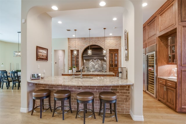 kitchen featuring light stone counters, glass insert cabinets, and a peninsula