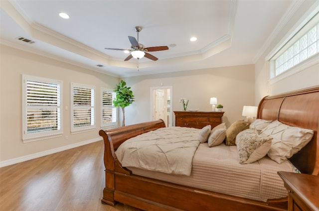 bedroom featuring ornamental molding, a tray ceiling, visible vents, and wood finished floors