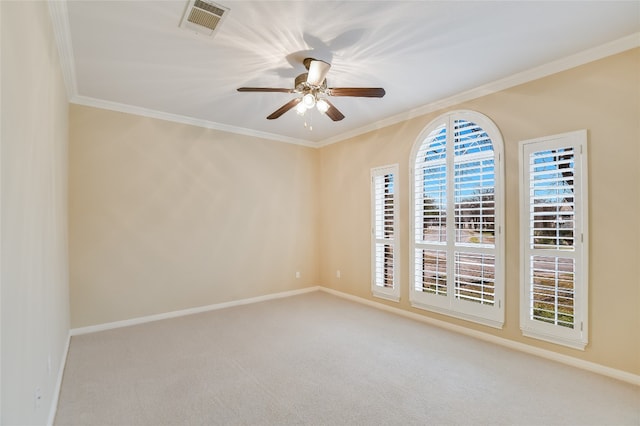 carpeted empty room with ceiling fan, visible vents, and ornamental molding