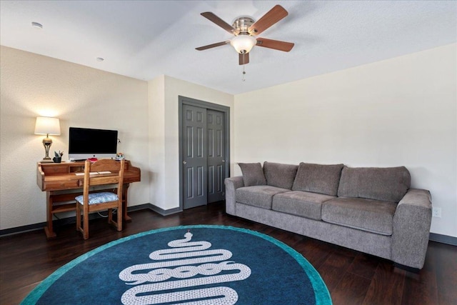 living room with a ceiling fan, baseboards, and wood finished floors