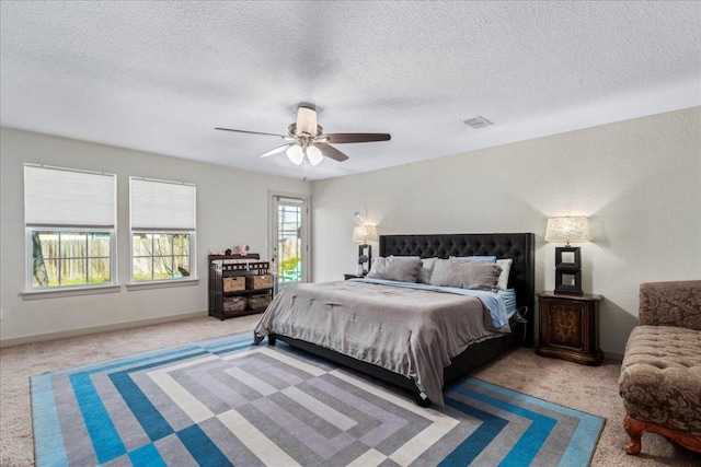 bedroom with a textured ceiling, carpet, and a ceiling fan