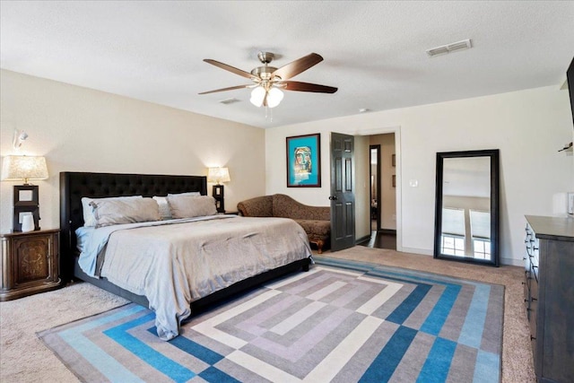 carpeted bedroom with ceiling fan, a textured ceiling, visible vents, and baseboards