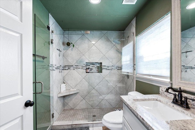 full bath with a stall shower, visible vents, vanity, and toilet