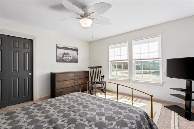 carpeted bedroom with ceiling fan and baseboards