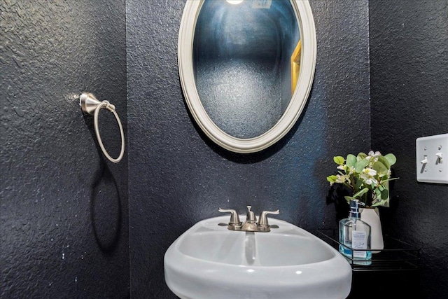 bathroom featuring a textured wall and a sink