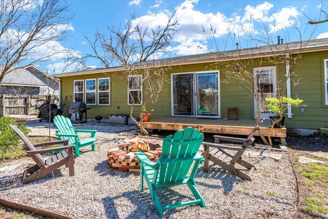 back of house with a deck, fence, and a fire pit