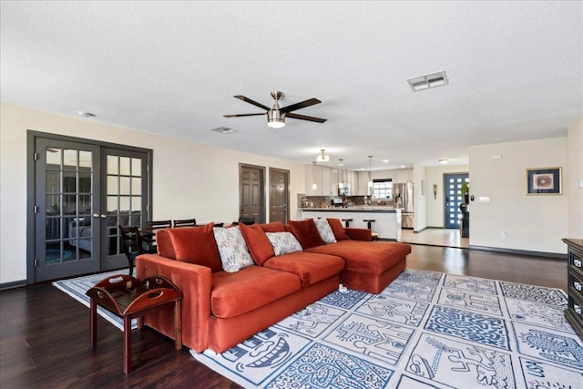 living room with a textured ceiling, french doors, wood finished floors, and visible vents