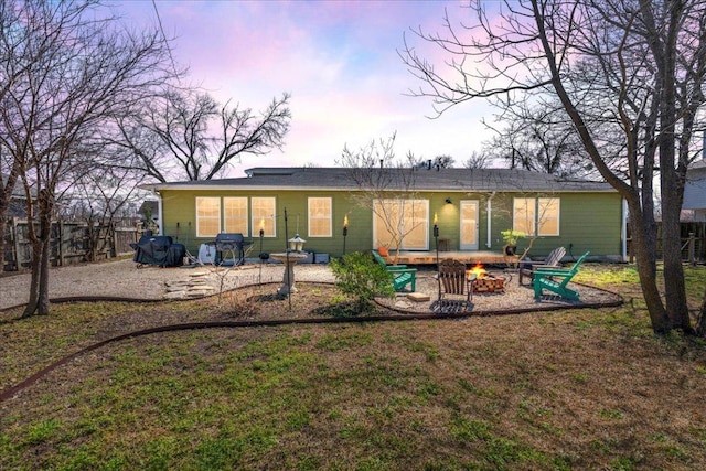 back of house at dusk with a patio, a fire pit, and fence